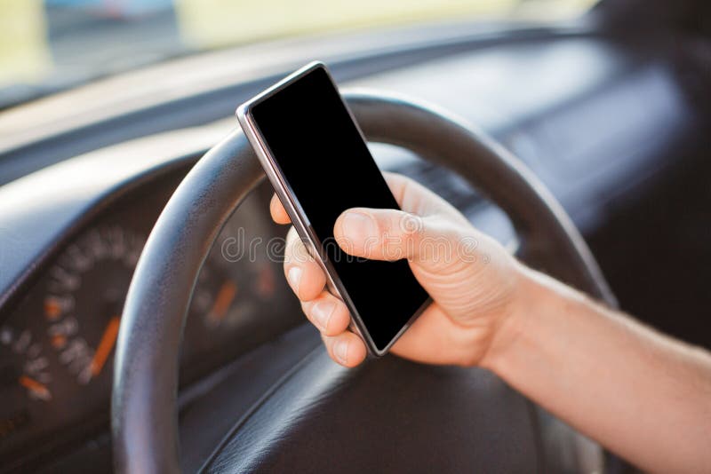 O homem irreconhecível mantém o telefone esperto no carro contra o fundo da roda, tela vazia da cópia para o texto do yout, mensa fotos de stock royalty free O homem irreconhecível mantém o telefone esperto no carro contra o fundo da roda, tela vazia da cópia para o texto do yout, mensa fotos de stock royalty free