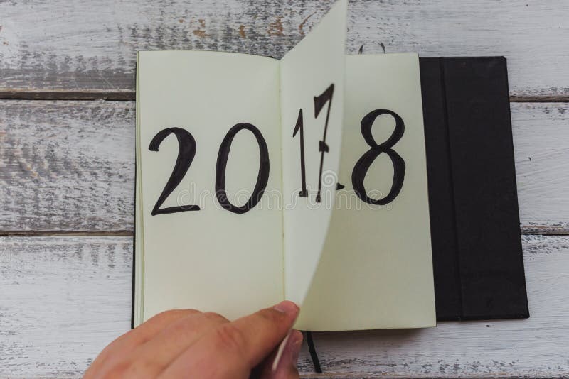 O homem lança a folha do bloco de notas na tabela de madeira branca 2017 estão girando, 2018 estão abrindo fotos de stock O homem lança a folha do bloco de notas na tabela de madeira branca 2017 estão girando, 2018 estão abrindo fotos de stock