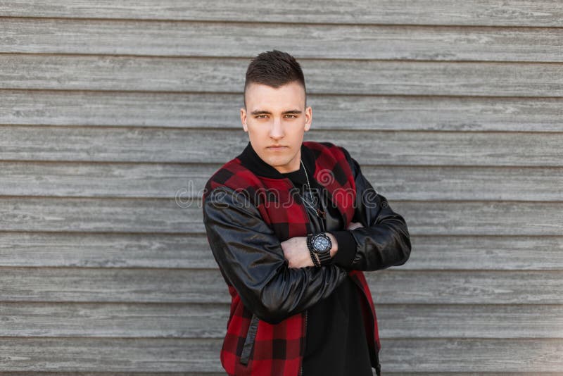 O homem novo atrativo em um revestimento da manta do vintage com um penteado à moda em um t-shirt com um pulso de disparo levanta imagens de stock royalty free O homem novo atrativo em um revestimento da manta do vintage com um penteado à moda em um t-shirt com um pulso de disparo levanta imagens de stock royalty free