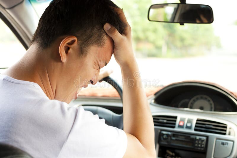 O homem novo cansado tem uma dor de cabeça ao conduzir o carro foto de stock O homem novo cansado tem uma dor de cabeça ao conduzir o carro foto de stock