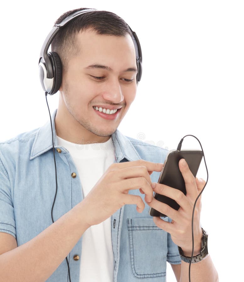 O homem novo considerável aprecia a música de escuta no telefone celular com hea fotografia de stock O homem novo considerável aprecia a música de escuta no telefone celular com hea fotografia de stock