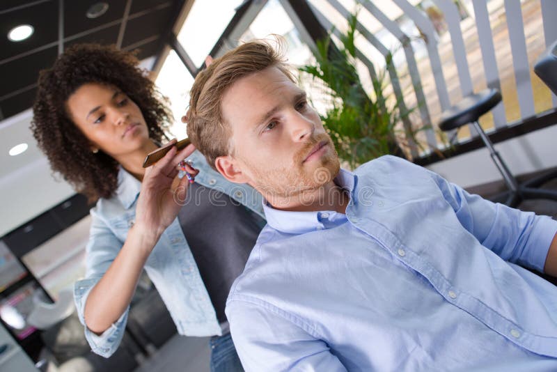 O homem novo corta o cabelo na barbearia bonita fotos de stock O homem novo corta o cabelo na barbearia bonita fotos de stock