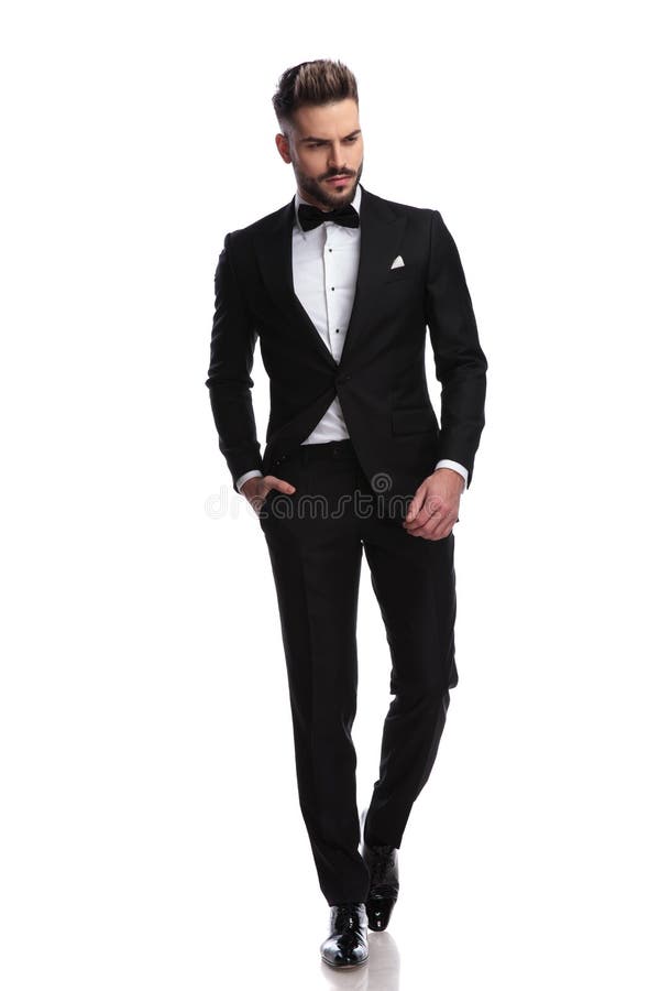 O homem novo da forma no smoking anda e olha para baixo imagem de stock O homem novo da forma no smoking anda e olha para baixo imagem de stock