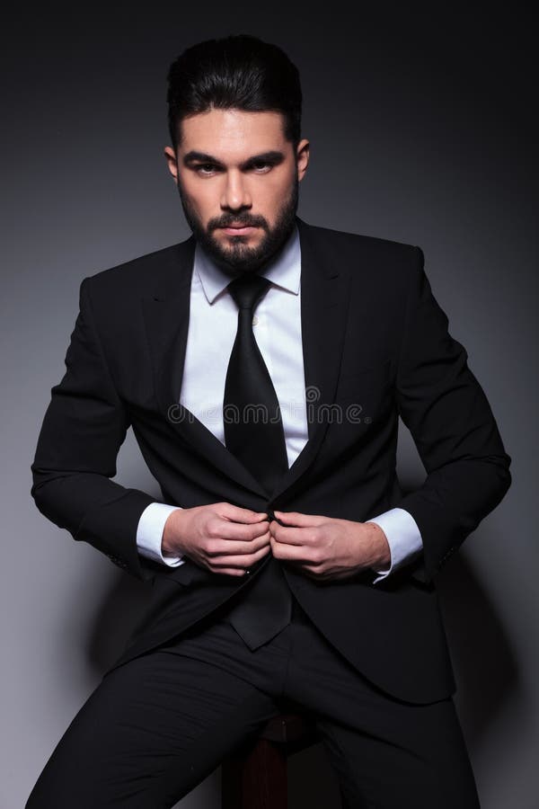 O homem novo da forma olha-o e abotoa-o o terno fotografia de stock O homem novo da forma olha-o e abotoa-o o terno fotografia de stock