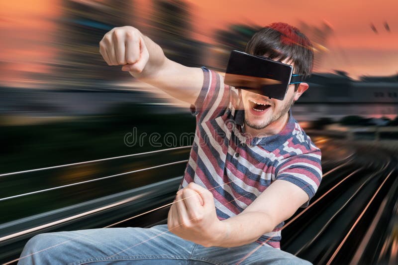 Happy young man is playing racing videogame in 3D virtual reality simulator using headset. Driving car in virtual reality. Happy young man is playing racing videogame in 3D virtual reality simulator using headset. Driving car in virtual reality.