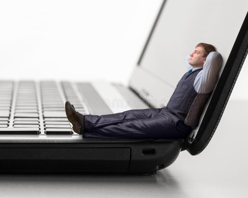 O homem novo senta-se no portátil imagem de stock O homem novo senta-se no portátil imagem de stock