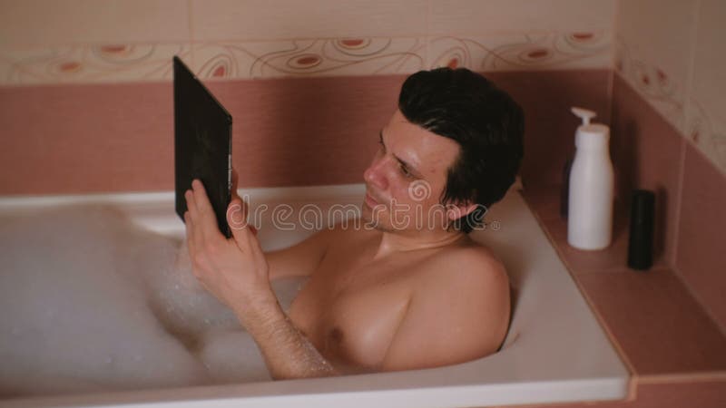 O homem novo toma um banho, datilografando uma mensagem na tabuleta