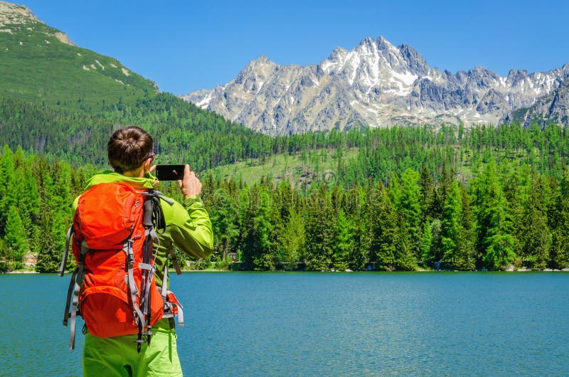 O homem novo toma uma foto do lago da montanha, Eslováquia imagens de stock O homem novo toma uma foto do lago da montanha, Eslováquia imagens de stock