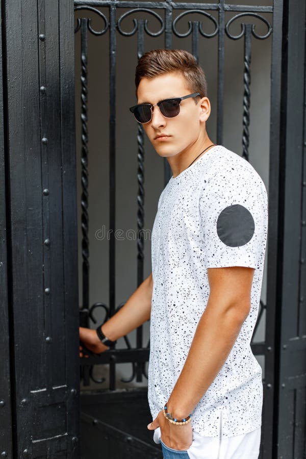 O homem novo à moda na camisa e nos óculos de sol brancos vem foto de stock royalty free O homem novo à moda na camisa e nos óculos de sol brancos vem foto de stock royalty free