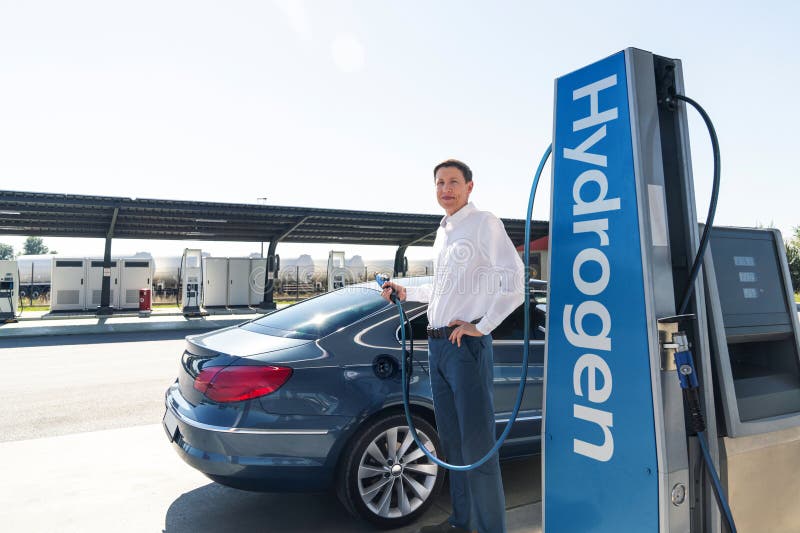 O homem segura um bocal a hidrogênio numa estação de reabastecimento de hidrogênio. Carro de reabastecimento com combustível de hi fotos de stock