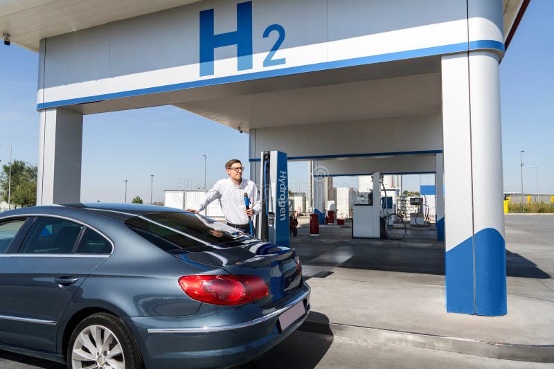 O homem segura um bocal a hidrogênio numa estação de reabastecimento de hidrogênio. Carro de reabastecimento com combustível de hi imagem de stock royalty free