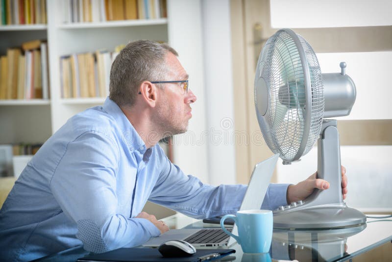 O homem sofre do calor no escritório ou em casa fotografia de stock royalty free O homem sofre do calor no escritório ou em casa fotografia de stock royalty free
