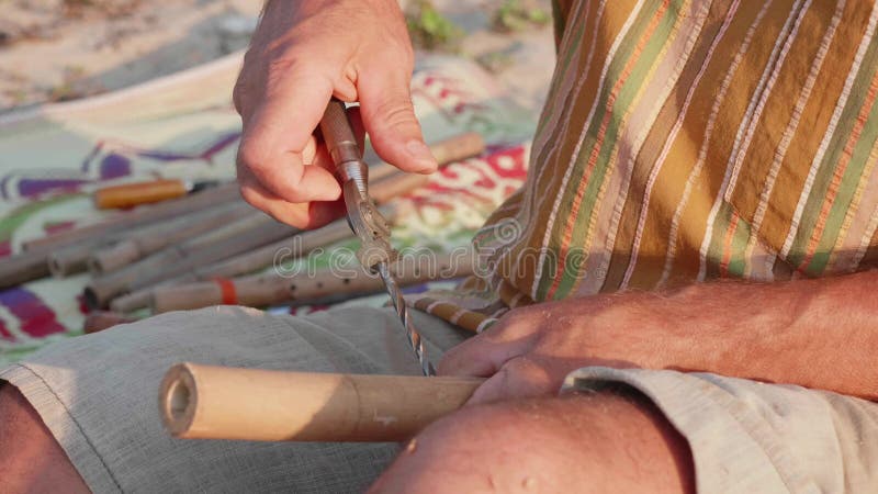 O homem superior senta-se na praia e flauta pelas mãos, close-up da fatura