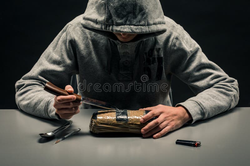 O homem é um viciado em drogas sentado à mesa faz drogas O conceito de problemas sociais da toxicodependência e da criminalidade fotos de stock royalty free O homem é um viciado em drogas sentado à mesa faz drogas O conceito de problemas sociais da toxicodependência e da criminalidade fotos de stock royalty free