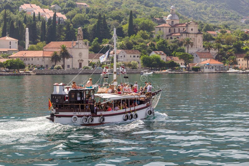 O iate velho de madeira com turistas está navegando na baía de Boka Kotorska no fundo da cidade de Prcanj fotos de stock O iate velho de madeira com turistas está navegando na baía de Boka Kotorska no fundo da cidade de Prcanj fotos de stock