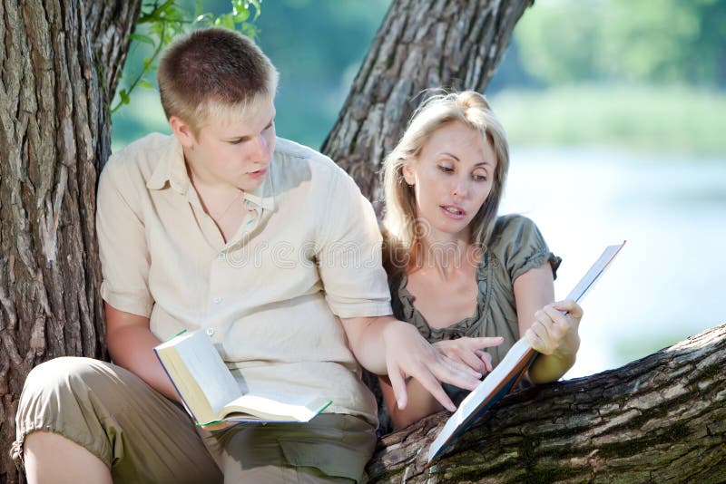 Young guy and the girl prepare for lessons, examination in spring park. Young guy and the girl prepare for lessons, examination in spring park