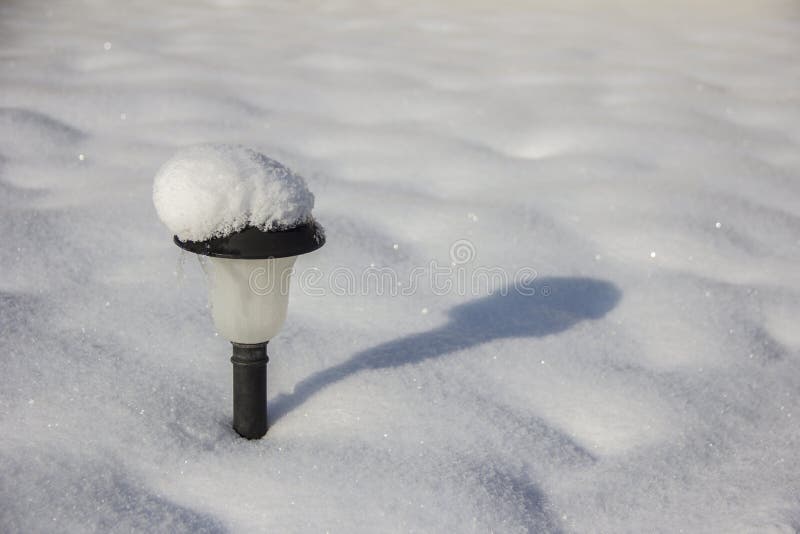 O jardim ilumina-se com a bateria solar na neve fotografia de stock royalty free O jardim ilumina-se com a bateria solar na neve fotografia de stock royalty free