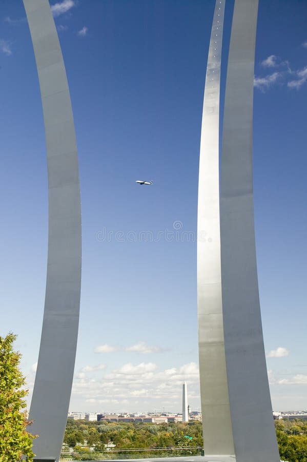 O jato comercial voa sobre o memorial da força aérea com os três pináculos crescentes e o Washington Monument na distância em uma foto de stock royalty free O jato comercial voa sobre o memorial da força aérea com os três pináculos crescentes e o Washington Monument na distância em uma foto de stock royalty free