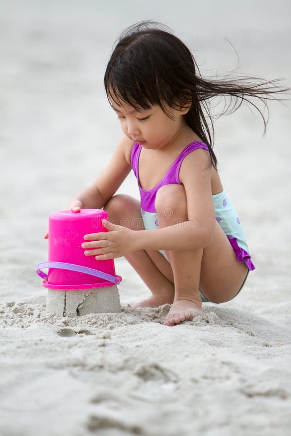 O jogo chinês pequeno asiático da menina lixa com brinquedos da praia foto de stock royalty free O jogo chinês pequeno asiático da menina lixa com brinquedos da praia foto de stock royalty free
