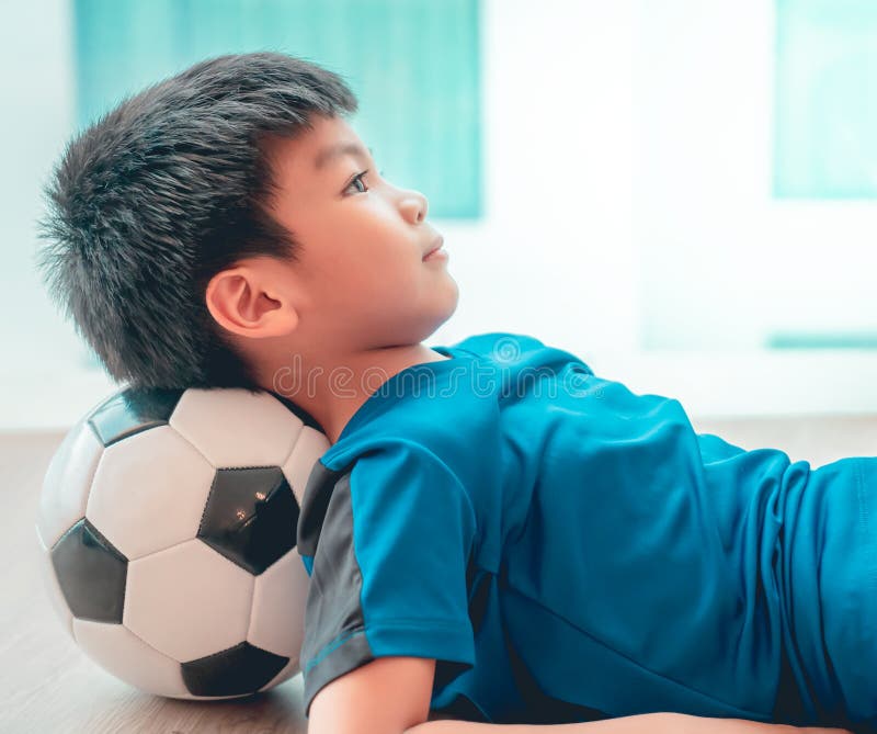 Menino Do Jogador De Futebol Que Pisa Na Bola Na Sala Imagem de