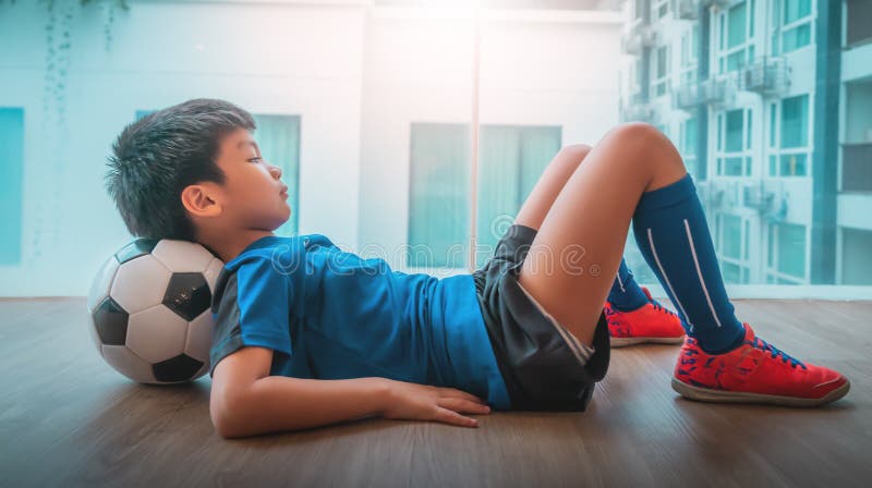 Menino Do Jogador De Futebol Que Pisa Na Bola Na Sala Imagem de