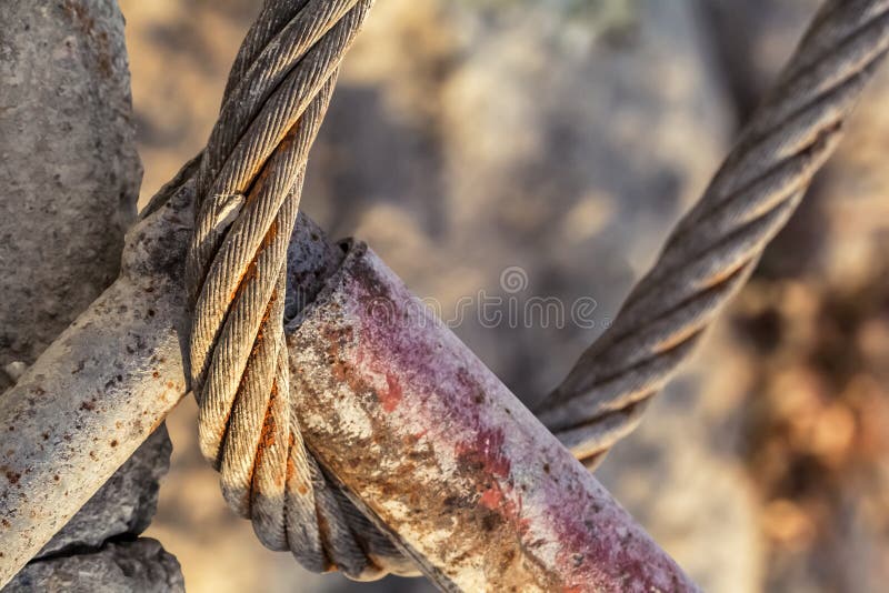 O laço de aço oxidado velho do cabo conectou a um detalhe tubular da construção do metal foto de stock royalty free O laço de aço oxidado velho do cabo conectou a um detalhe tubular da construção do metal foto de stock royalty free