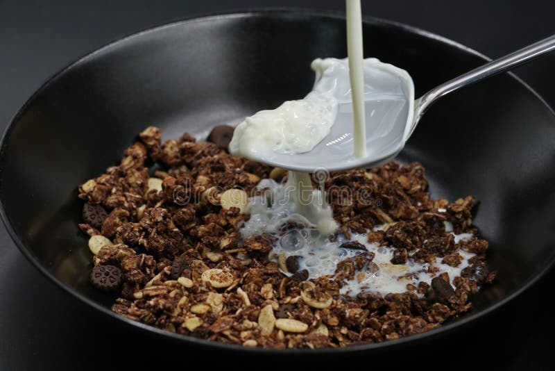 O leite flui na colher no muesli do chocolate, cereais fotografia de stock O leite flui na colher no muesli do chocolate, cereais fotografia de stock