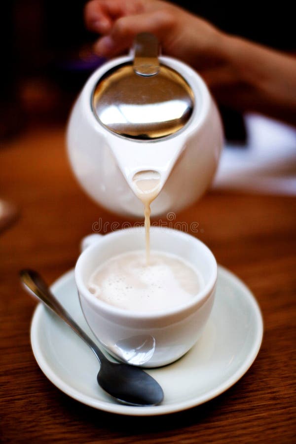 O lovitură de închidere verticală a unui ceainic alb care toarnă cafea într-o ceașcă royalty free stock photo