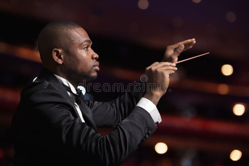 Young conductor with baton raised at a performance. Young conductor with baton raised at a performance