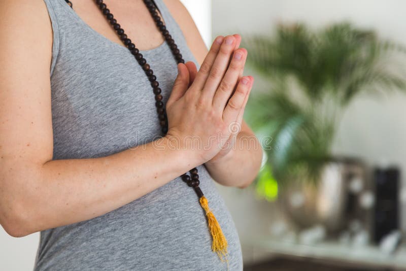 O mala vestindo da mulher gravida nova perla com mãos na posição do namaste que faz a ioga imagens de stock O mala vestindo da mulher gravida nova perla com mãos na posição do namaste que faz a ioga imagens de stock