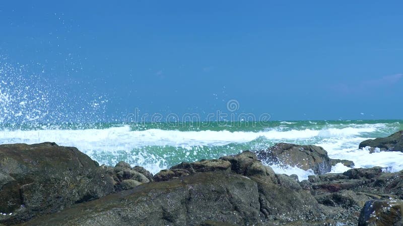 O mar acena o espirro na praia rochosa na paisagem do céu azul Feche acima das ondas de água que quebram na costa rochoso no ocea