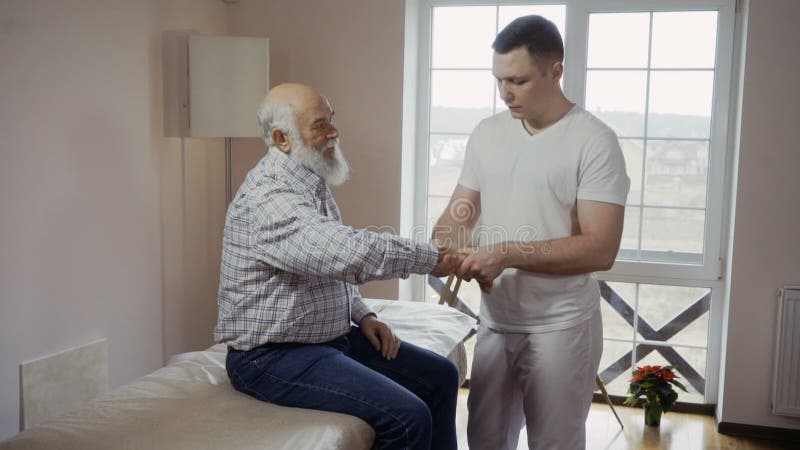 O massagista profissional examina a dor no pulso de um paciente idoso