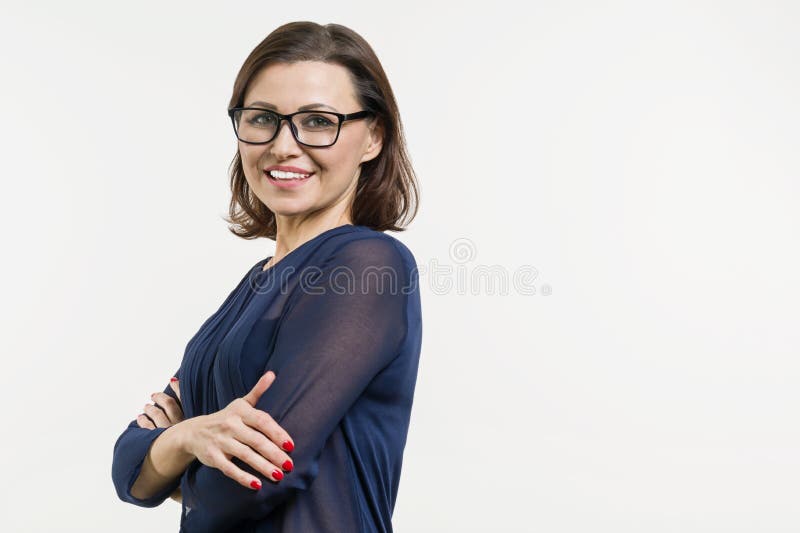 O meio de sorriso envelheceu a mulher com os braços dobrados no fundo branco foto de stock O meio de sorriso envelheceu a mulher com os braços dobrados no fundo branco foto de stock