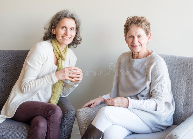 O meio envelheceu a filha no lenço verde que sorri ao lado de uma mãe mais idosa fotografia de stock O meio envelheceu a filha no lenço verde que sorri ao lado de uma mãe mais idosa fotografia de stock