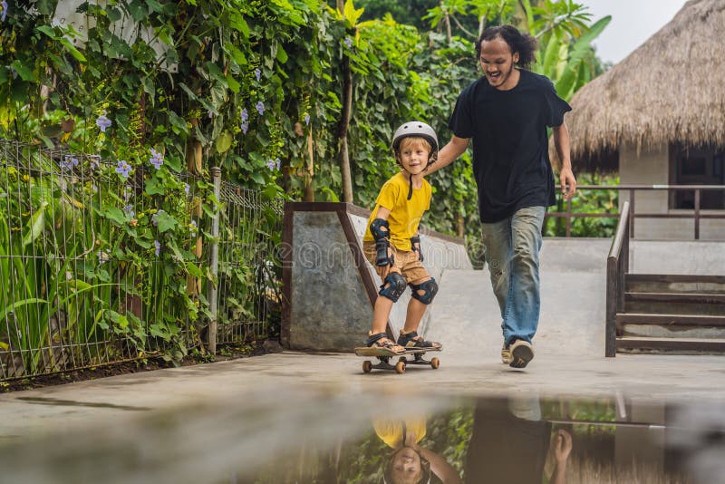 O menino atlético aprende ao skate com um instrutor em um parque do patim Educação das crianças, esportes imagem de stock O menino atlético aprende ao skate com um instrutor em um parque do patim Educação das crianças, esportes imagem de stock
