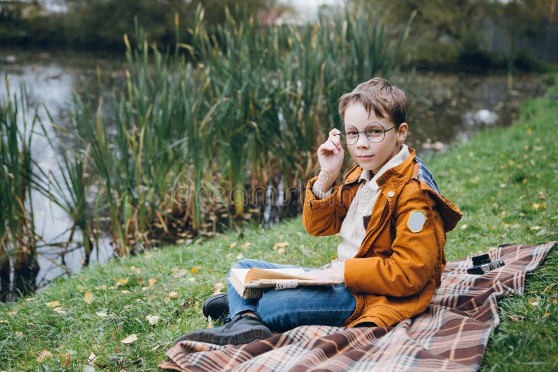 O menino bonito anda e levanta em um parque colorido do outono foto de stock O menino bonito anda e levanta em um parque colorido do outono foto de stock