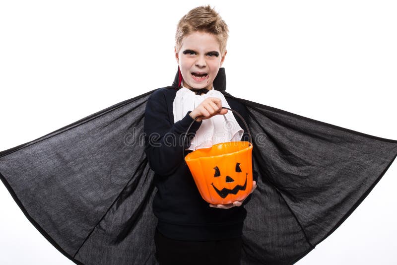O menino com cesta da abóbora vestiu-se como o vampiro para o partido de Dia das Bruxas imagem de stock royalty free O menino com cesta da abóbora vestiu-se como o vampiro para o partido de Dia das Bruxas imagem de stock royalty free