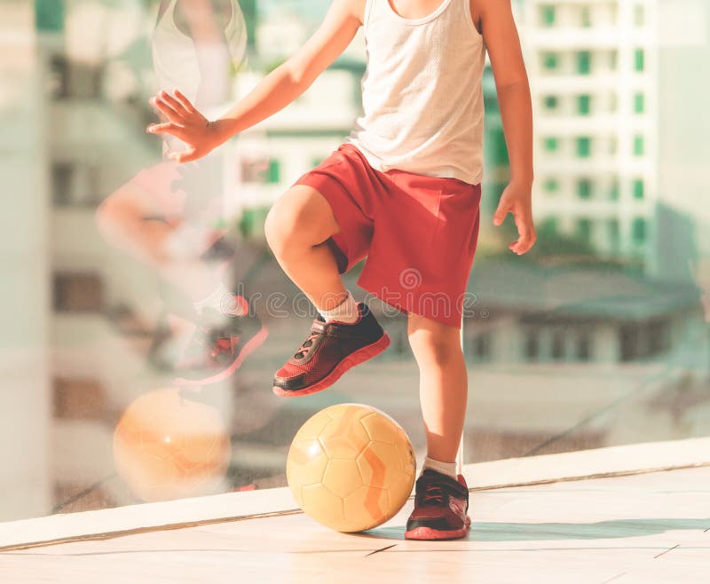 Menino Do Jogador De Futebol Que Pisa Na Bola Na Sala Imagem de