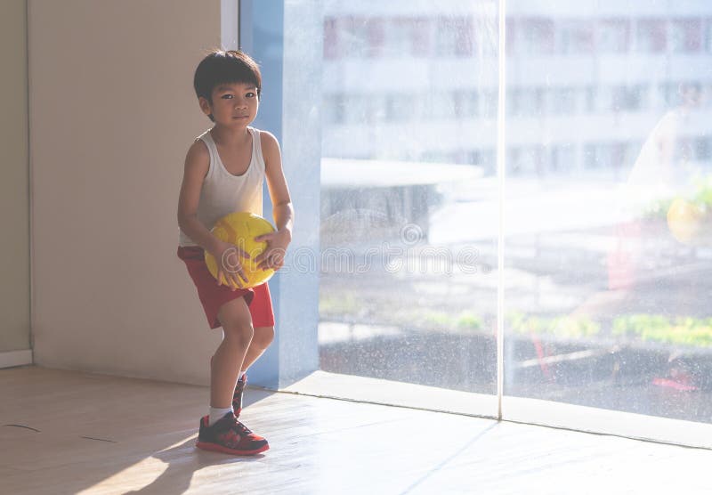 Menino Do Jogador De Futebol Que Pisa Na Bola Na Sala Imagem de