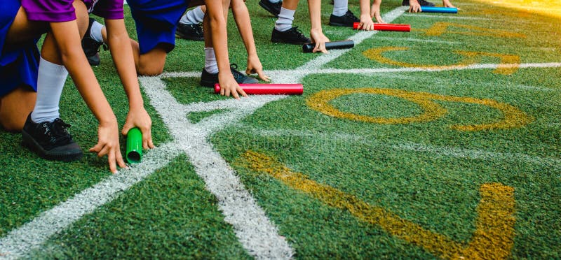O menino dos estudantes prepara-se a deixar começar para o menino da raça de relé no dia dos esportes da escola fotos de stock O menino dos estudantes prepara-se a deixar começar para o menino da raça de relé no dia dos esportes da escola fotos de stock