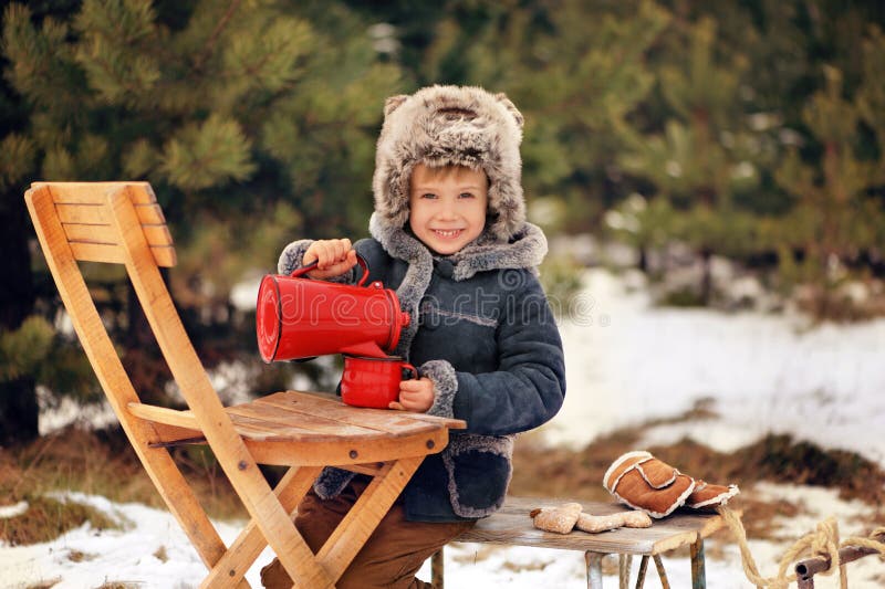 O menino está jogando com trenós fora no inverno imagem de stock O menino está jogando com trenós fora no inverno imagem de stock