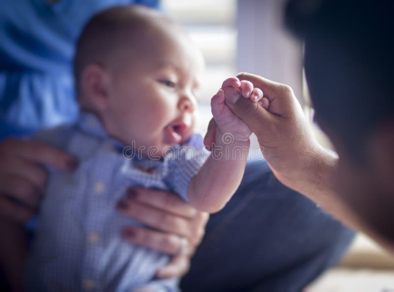 O menino infantil bonito da raça misturada guardara o polegar do pai imagem de stock O menino infantil bonito da raça misturada guardara o polegar do pai imagem de stock