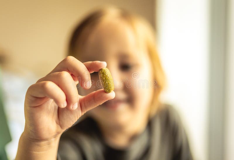 O menino novo guarda a vitamina ou o comprimido da prescrição com os dedos na frente da cara Conceito dos cuidados m?dicos Concei imagem de stock royalty free O menino novo guarda a vitamina ou o comprimido da prescrição com os dedos na frente da cara Conceito dos cuidados m?dicos Concei imagem de stock royalty free