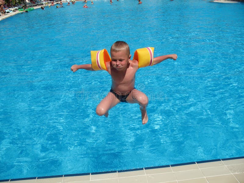 O menino que salta na piscina fotos de stock O menino que salta na piscina fotos de stock