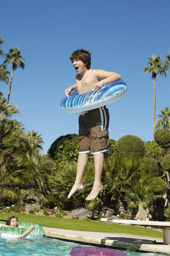 O menino que salta na piscina imagem de stock O menino que salta na piscina imagem de stock