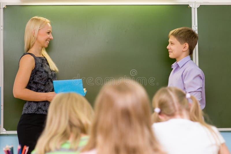 O menino responde a perguntas dos professores perto de uma administração da escola fotos de stock royalty free O menino responde a perguntas dos professores perto de uma administração da escola fotos de stock royalty free