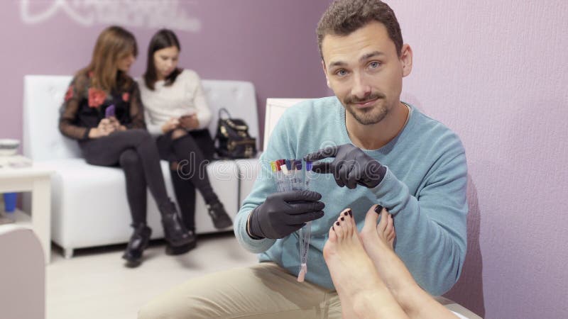 O mestre do pedicure escolhe a cor da laca do prego