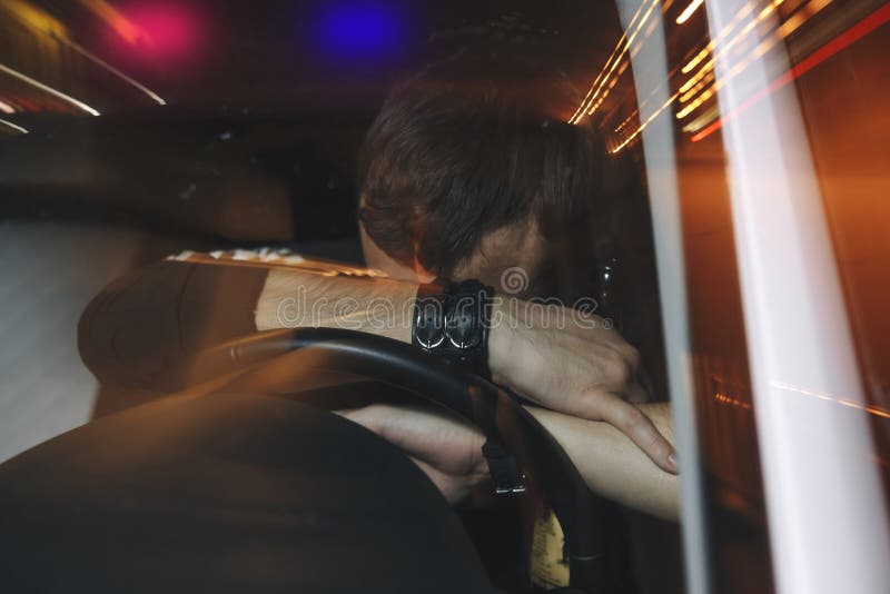 O motorista masculino virado é condução travada sob a influência do álcool Equipe a coberta de sua cara da luz do carro de políci imagens de stock royalty free O motorista masculino virado é condução travada sob a influência do álcool Equipe a coberta de sua cara da luz do carro de políci imagens de stock royalty free