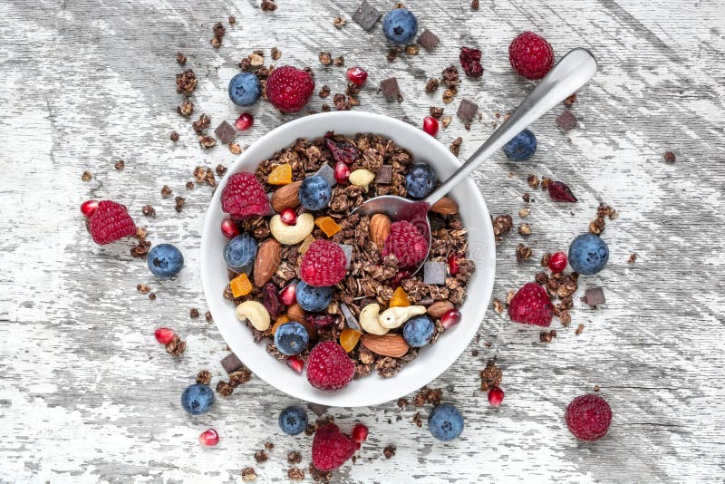 O muesli caseiro do chocolate ou o granola em uma bacia com uma colher, bagas, secaram frutos e porcas foto de stock royalty free O muesli caseiro do chocolate ou o granola em uma bacia com uma colher, bagas, secaram frutos e porcas foto de stock royalty free