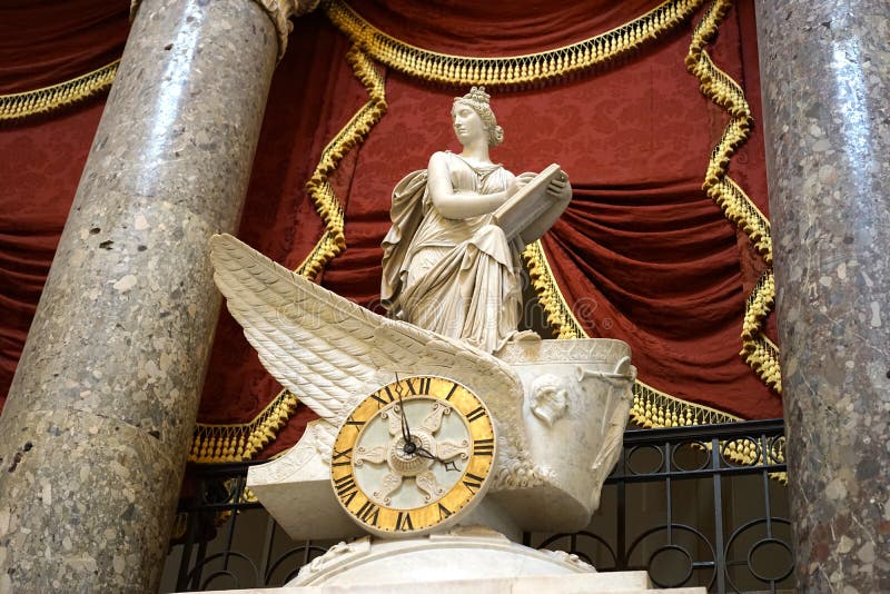 Above the Capitol Rotunda door in the US Capitol building, Washington, DC. is the Car of History by Carlo Franzoni. The neoclassical marble sculpture depicts Clio, the Muse of History, riding in the chariot of Time and recording historical events in the National Statuary Hall. The chariot wheel holds the chamber`s clock. Above the Capitol Rotunda door in the US Capitol building, Washington, DC. is the Car of History by Carlo Franzoni. The neoclassical marble sculpture depicts Clio, the Muse of History, riding in the chariot of Time and recording historical events in the National Statuary Hall. The chariot wheel holds the chamber`s clock.